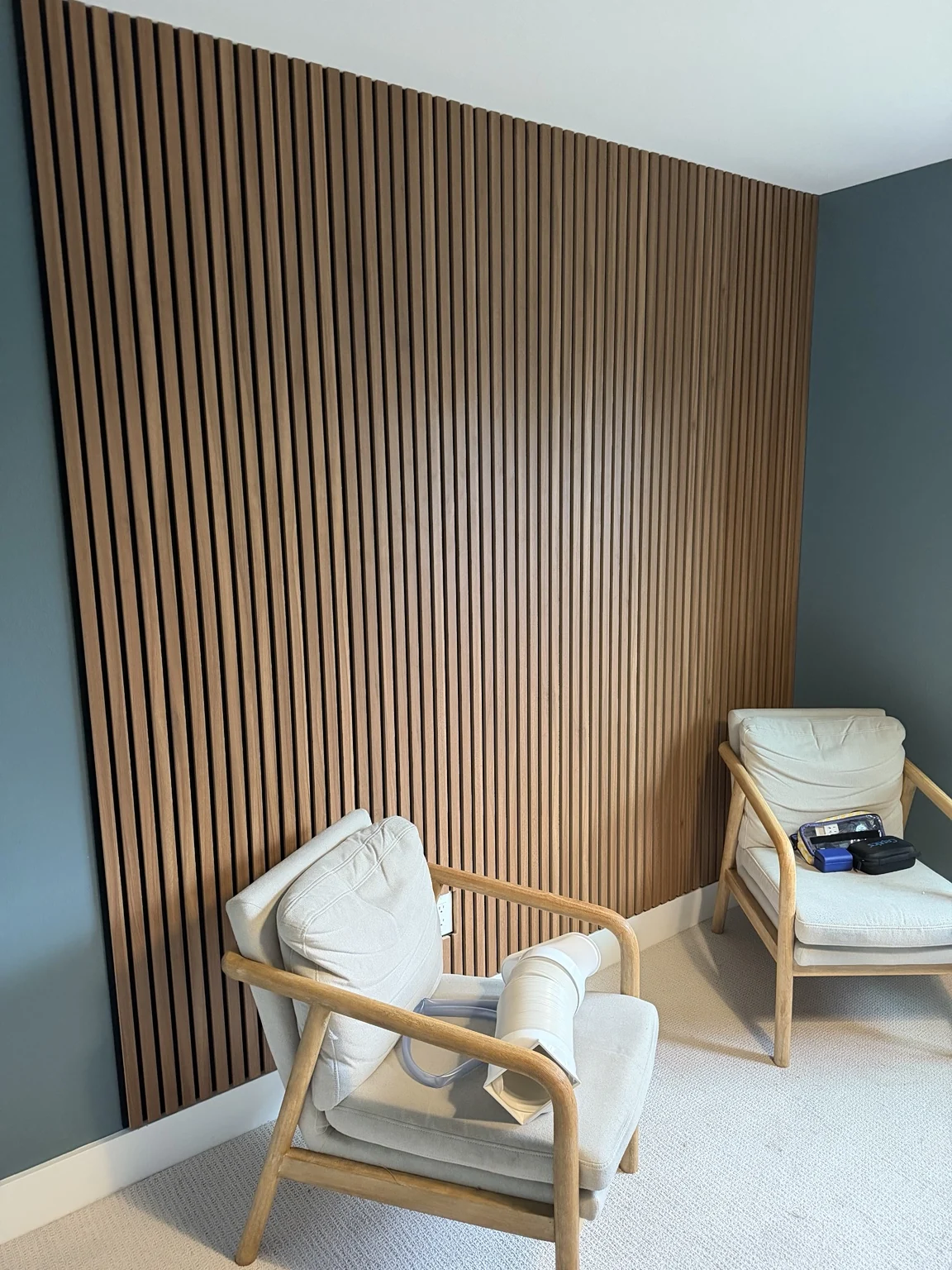 Installed wood slat accent wall behind two armchairs.