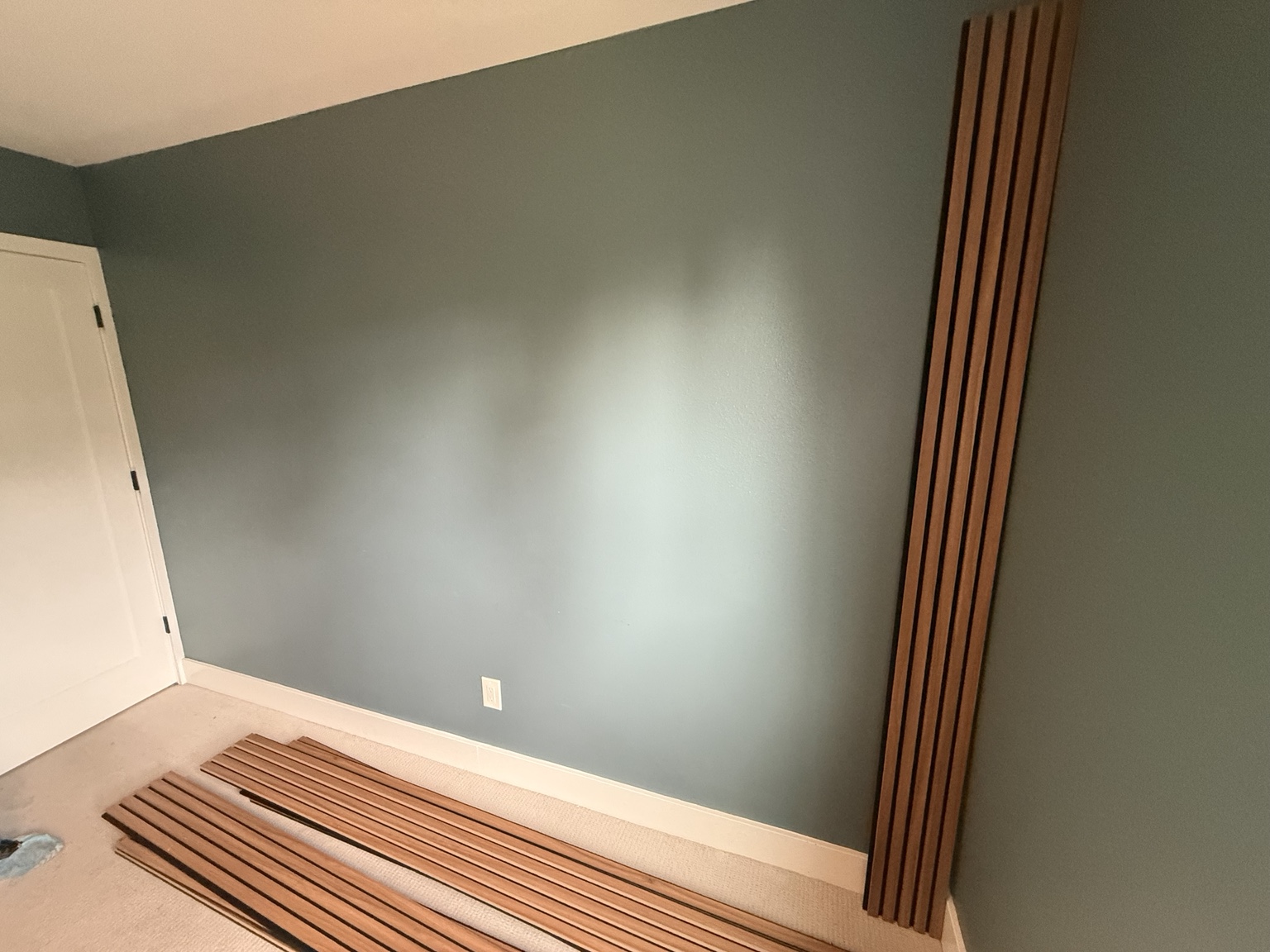 Wood slat panels laid out beside the wall during installation